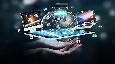 Two hands holding a digital globe surrounded by floating technology devices—laptops, tablets, and smartphones—alongside icons representing various digital services and applications.